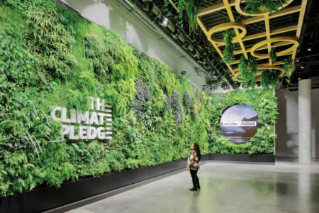A person stands in a large indoor space with walls covered in lush greenery. The words 