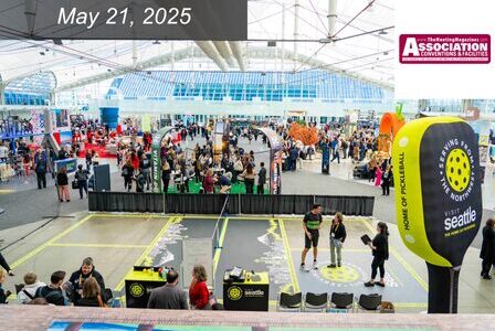 A busy indoor convention with crowds, pickleball courts, and booths.