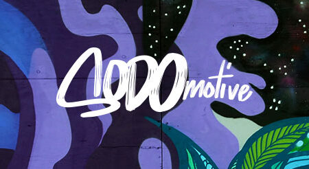 A vibrant mural featuring abstract shapes in purple, blue, and black, with green leaf-like patterns. The word "locomotive" is written in stylized white lettering across the center.